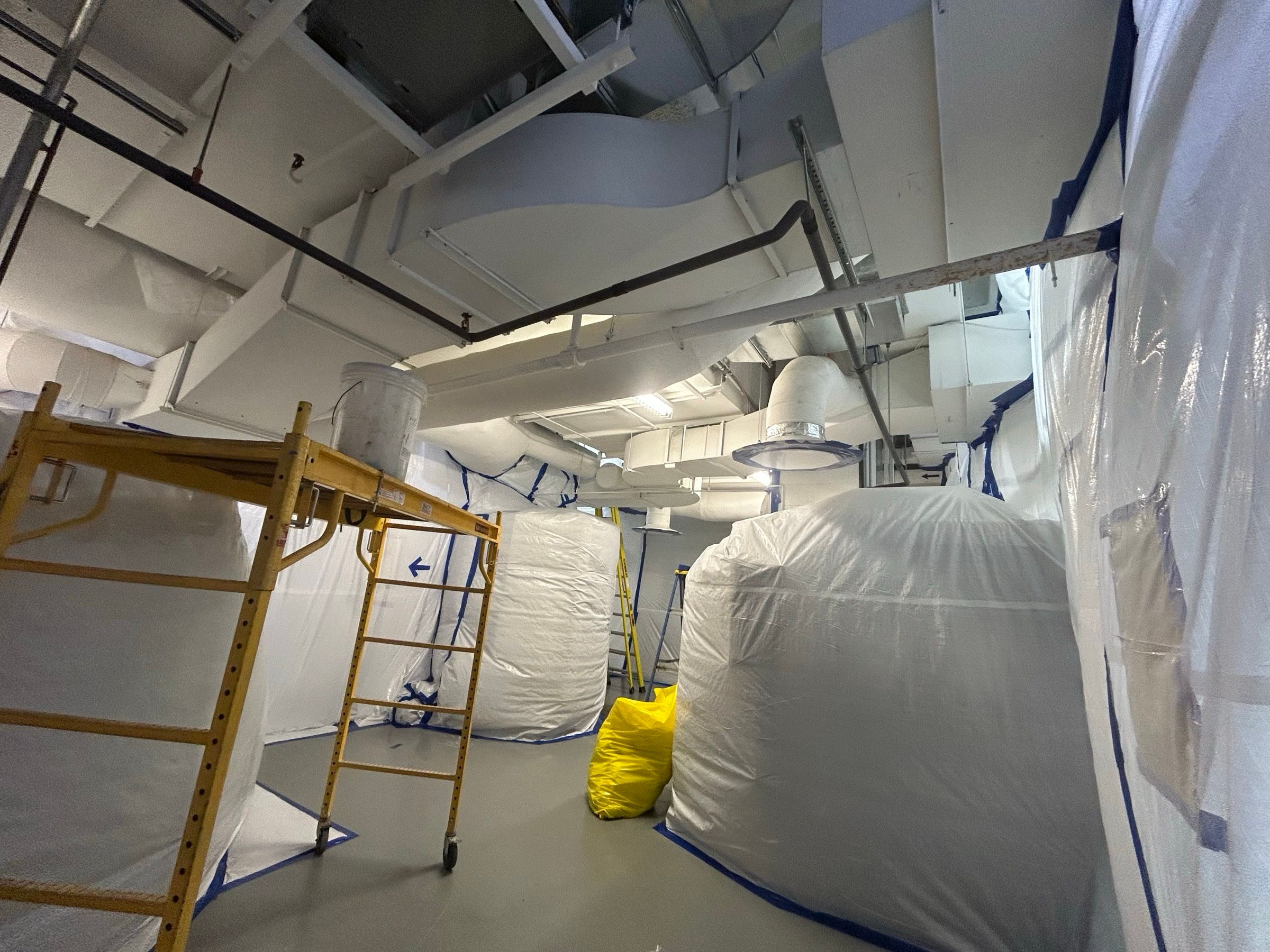 Aire de travail confinée au polyéthylène, équipements emballés et échafaudage, pendant une décontamination