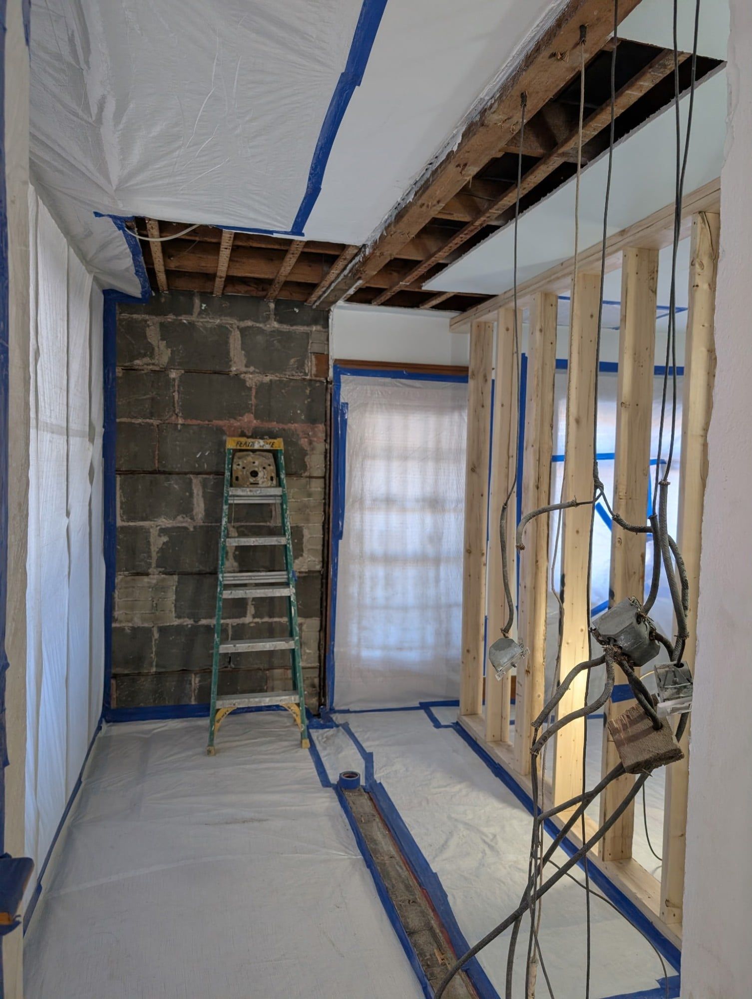 Room sealed in polyethylene, ceiling opened to the joists and block wall exposed
