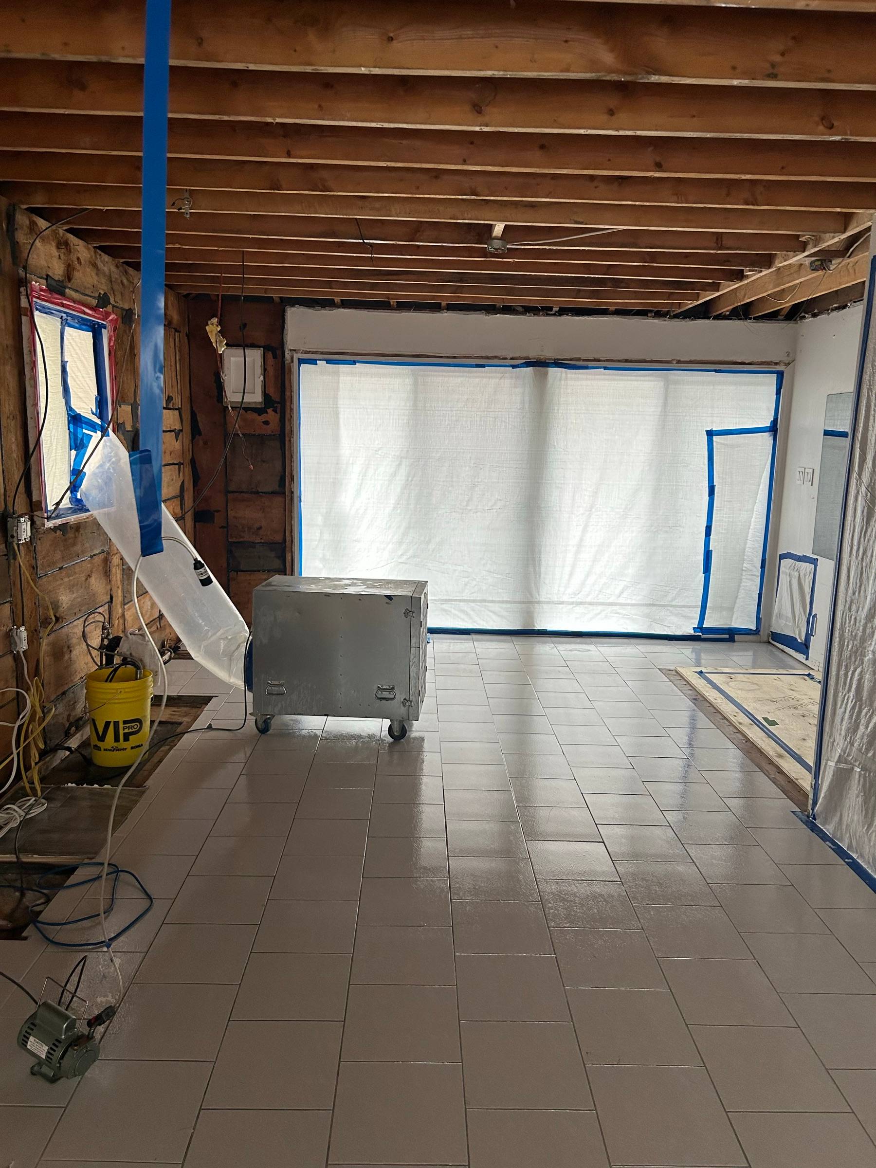 La même pièce en zone confinée au polyéthylène, plafond retiré jusqu'aux solives et épurateur d'air HEPA