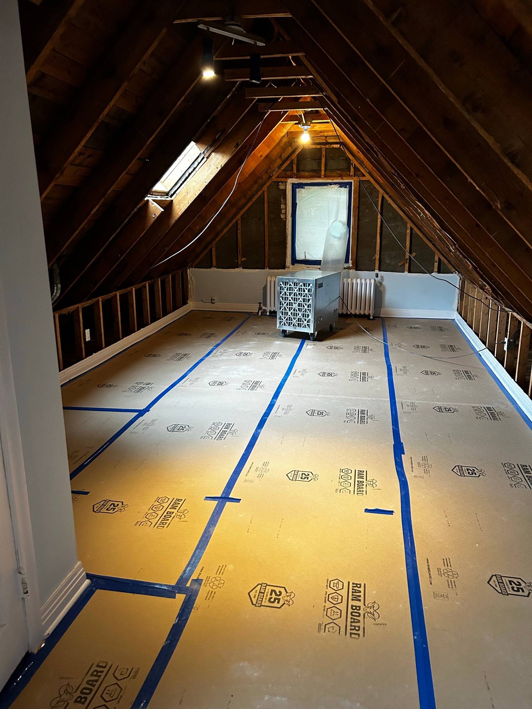 Combles d'une maison protégés au carton Ram Board, épurateur d'air HEPA installé dans l'aire de travail