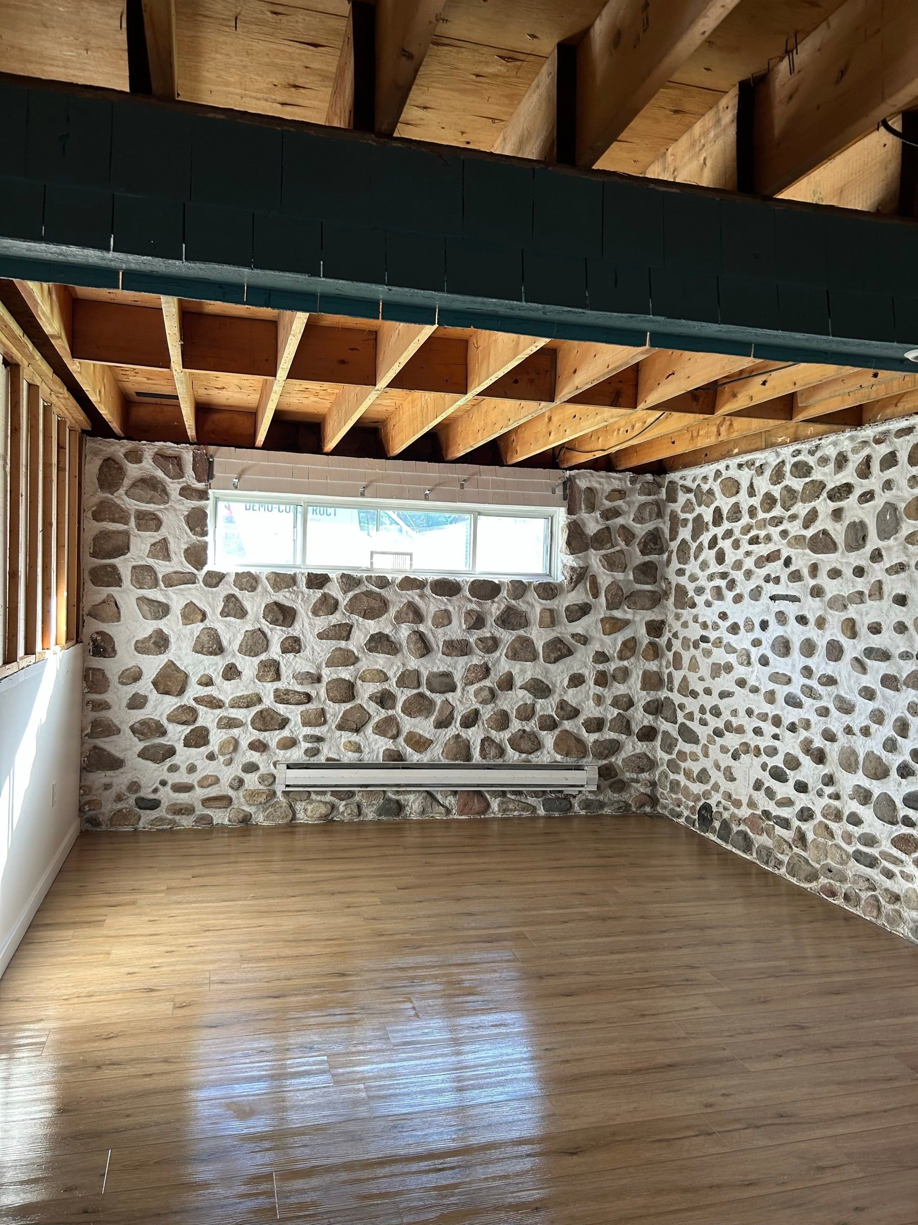 Basement with stone walls, ceiling stripped down to the joists after removal